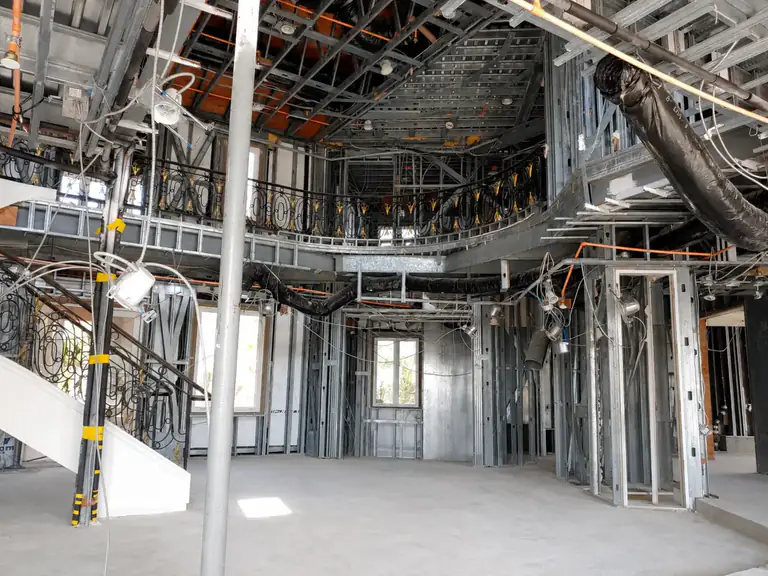 Two-story residential great room framed in cold-formed steel with steel wall studs, ceiling framing and a curved balcony structure